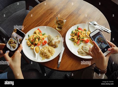 Women blogger takes photos of her food in a cafe using mobile phone ...