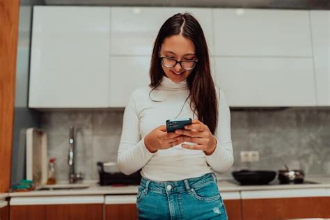 Premium Photo | A young woman usinga a smartphone while cooking in the ...