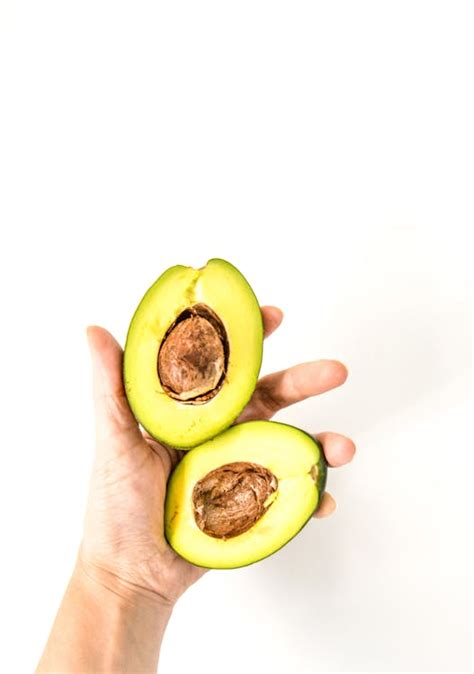 Fresh Avocado Halves in Hand on White Background · Free Stock Photo