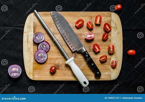 A Knife Sharpener and a Chef Knife on a Cutting Board with Vegetables ...