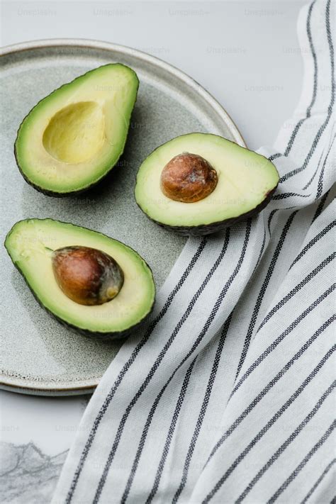 An avocado cut in half on a marble counter top photo – Avocado Image on ...