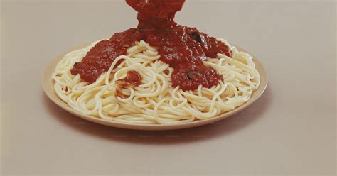 A spoon pouring sauce onto a plate of spaghetti photo – Tomato sauce ...