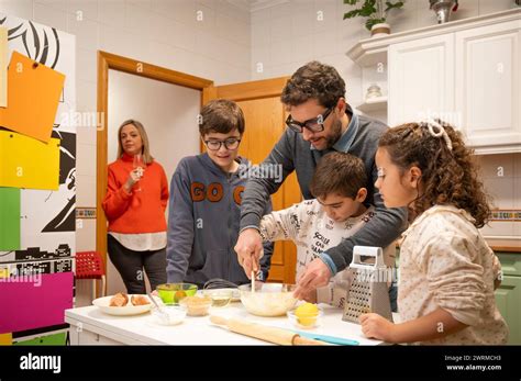 A family enjoys a cooking session together in a well-lit kitchen, with ...