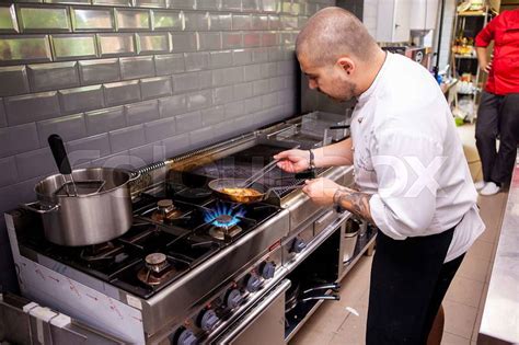 Chef cooking delicious meal in his restaurant kitchen | Colourbox